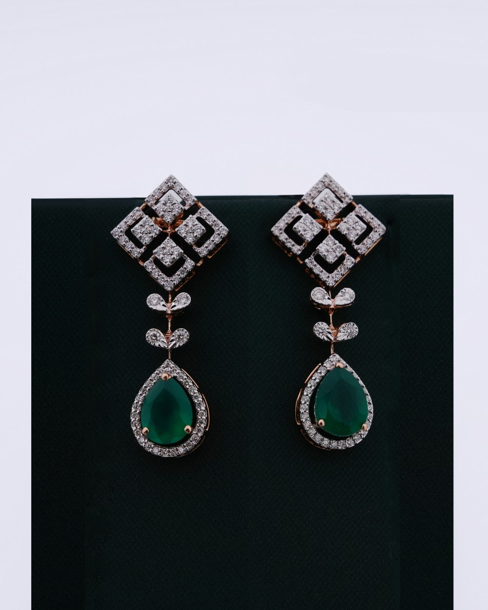 Pair of diamond and emerald earrings on a black background