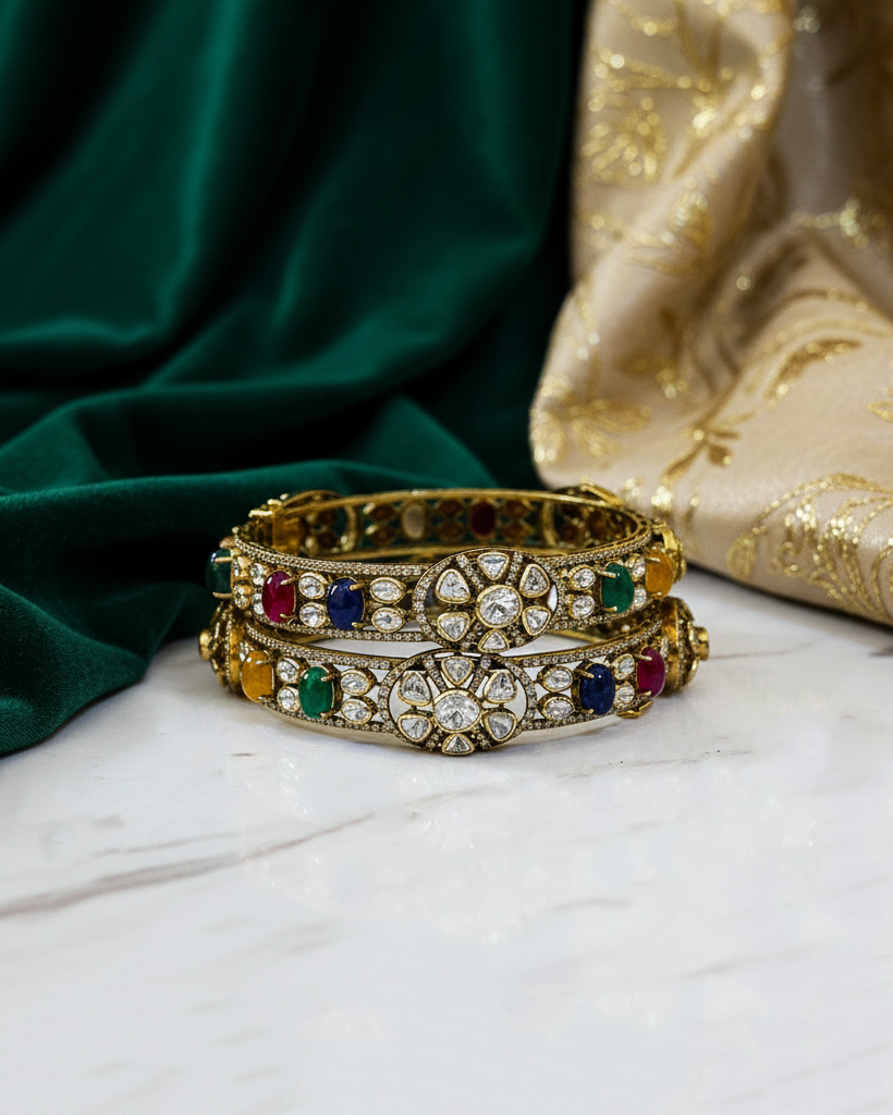 Decorative bangles with gemstones on a marble surface with green fabric in the background