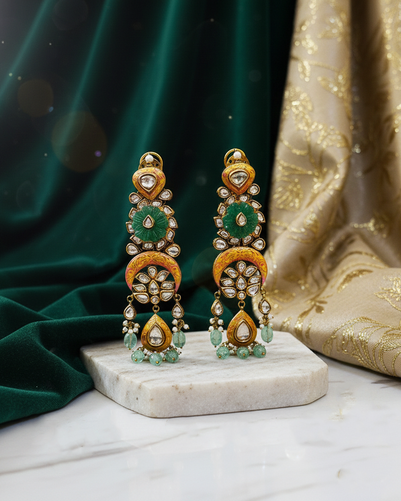 Pair of ornate earrings on a marble stand with a green and gold fabric background