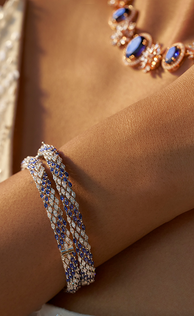 Close-up of a person's wrist wearing a bracelet with blue stones on a neutral background