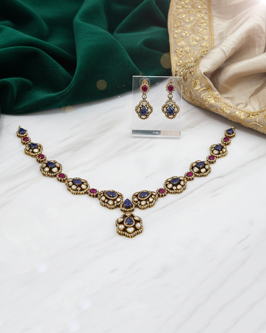 Jewelry set with necklace and earrings on a white surface with green fabric in the background